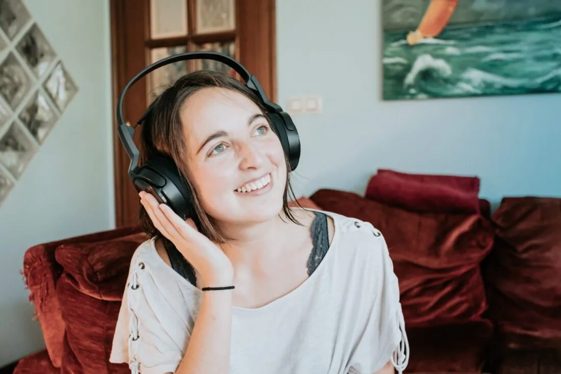 woman wears headphones with one hand up smiling scaled 1 1400x933 1