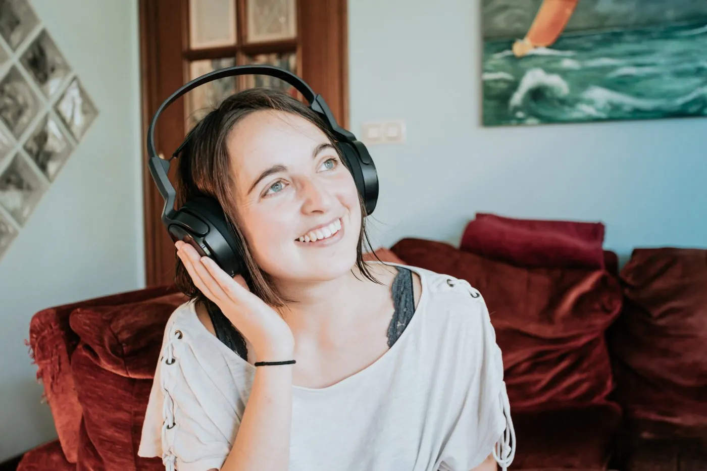 woman wears headphones with one hand up smiling scaled 1 1400x933 1